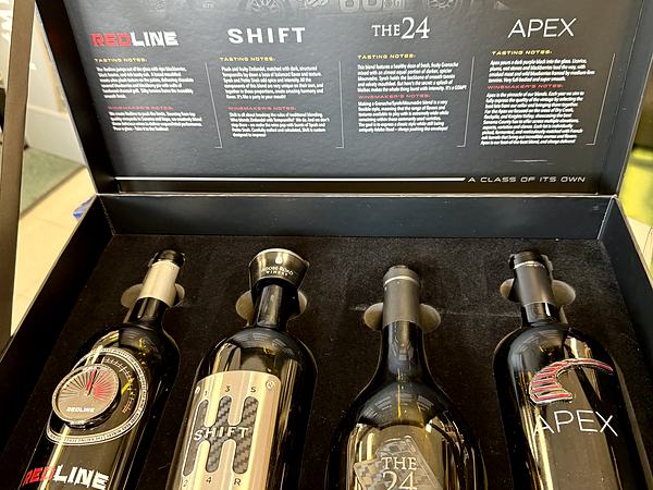 An open presentation box holding four dark wine bottles labelled Redline, Shift, The 24 and Apex.